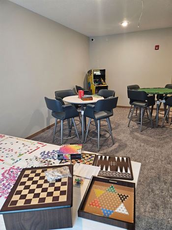 A room with a table, chairs, and a checkerboard on the table.